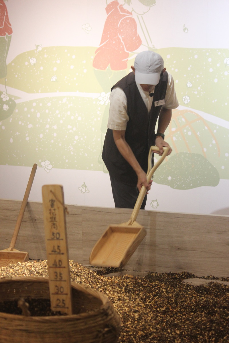博物館人員在茉莉窨花展示池中模擬傳統窨花茶翻花步驟，呈現花香入茶的工藝過程
