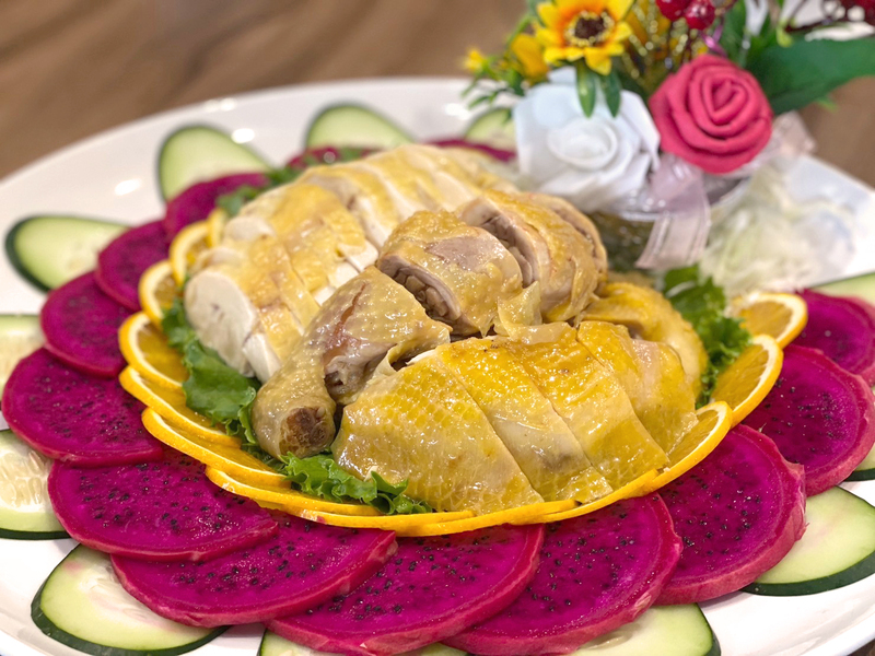 客茶樓 2026 金馬迎新開運年菜｜客家白斬雞擺盤，金黃鮮嫩的雞肉搭配火龍果、黃瓜與橙片點綴，呈現新春團圓料理。