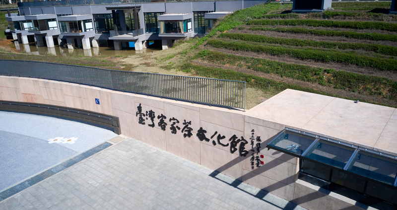 臺灣客家茶文化館正面入口，左側為廣場空間，右側為茶園階梯景觀，展現融合自然與文化的建築特色